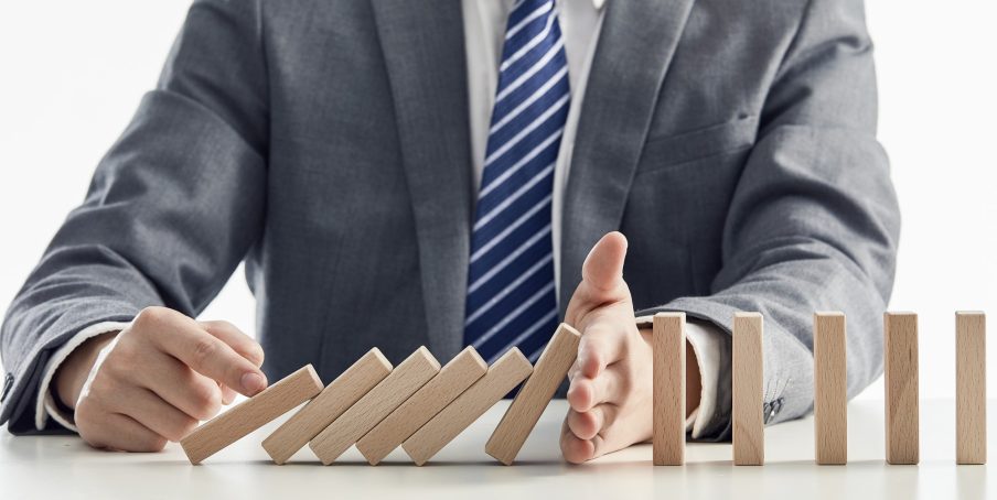 businessman-suit-protecting-wooden-blocks-from-falling-domino-effect